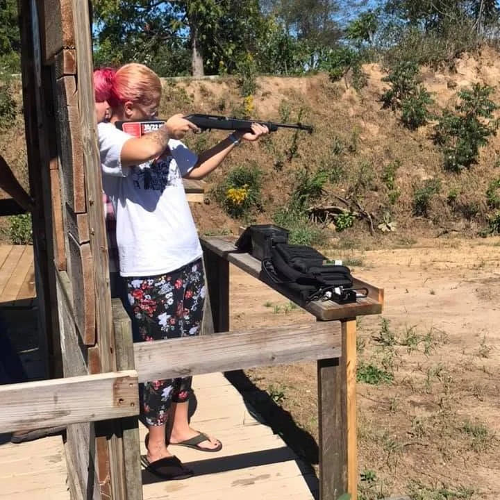 Member shooting shotgun from the porch